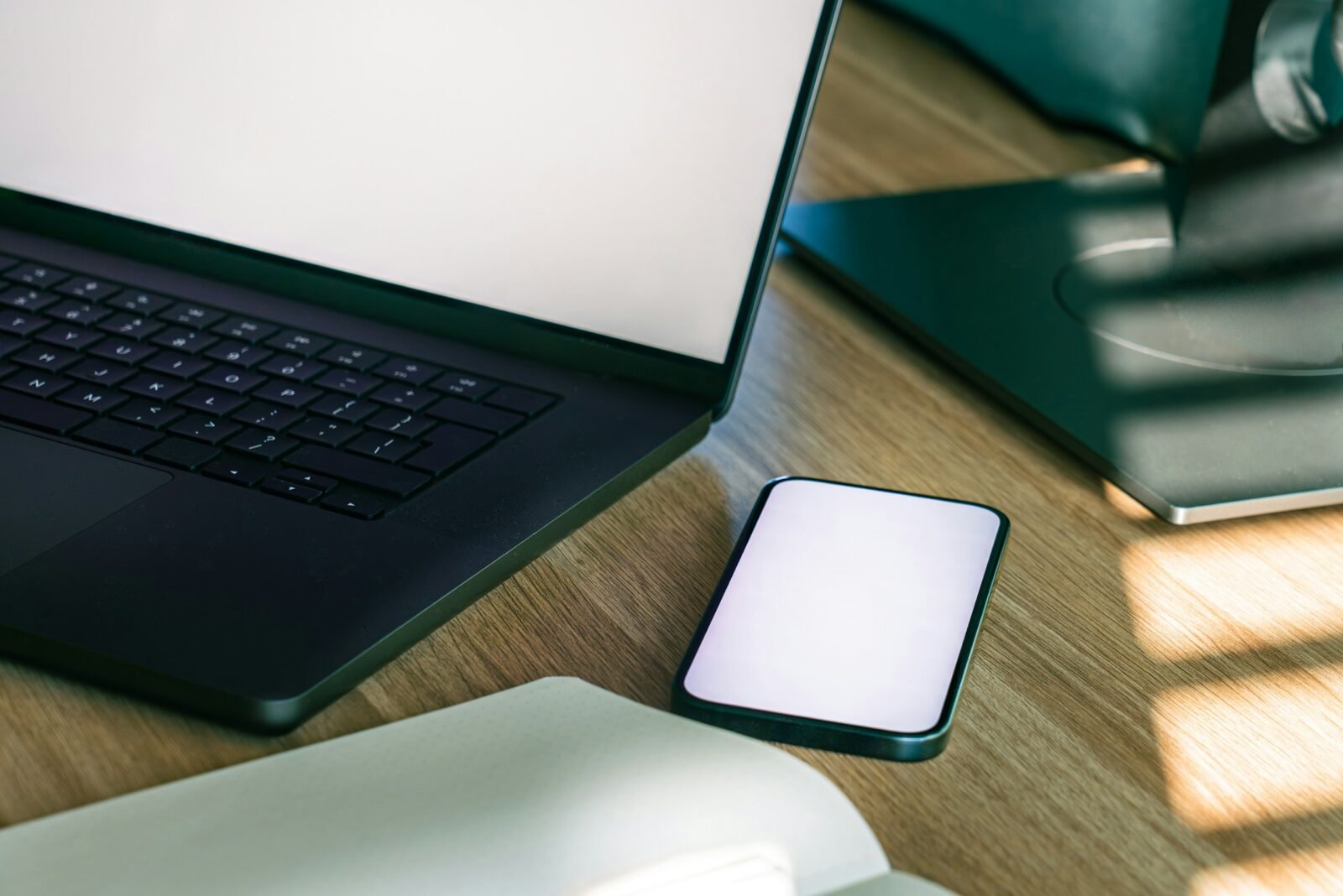 Portátil y teléfono móvil con las pantallas en blanco sobre una mesa