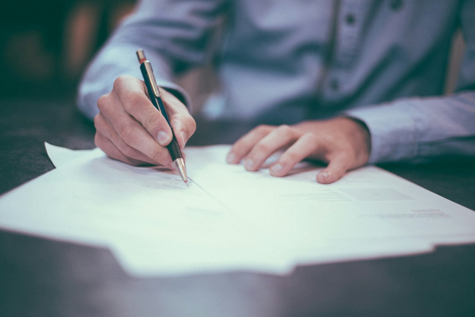 Persona que firma un documento sobre una mesa