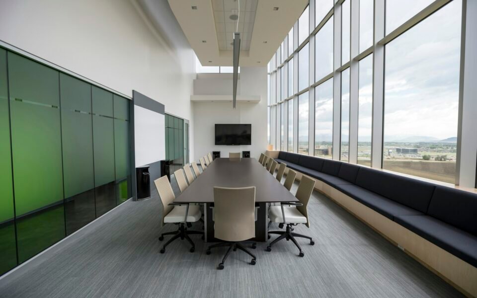 Sala de consejo vacía con mesa larga y grandes ventanales