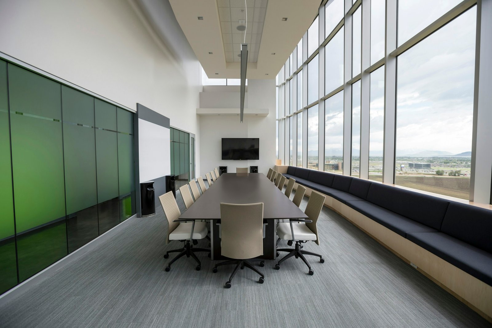Sala de consejo vacía con mesa larga y grandes ventanales
