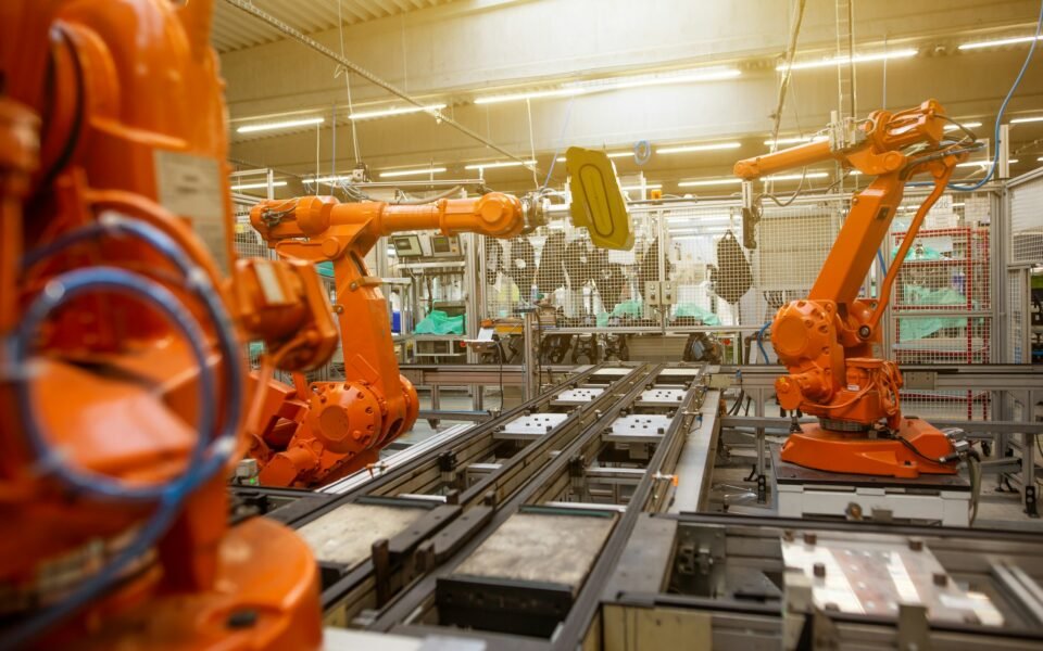 Brazos robóticos naranjas en una línea de producción automatizada