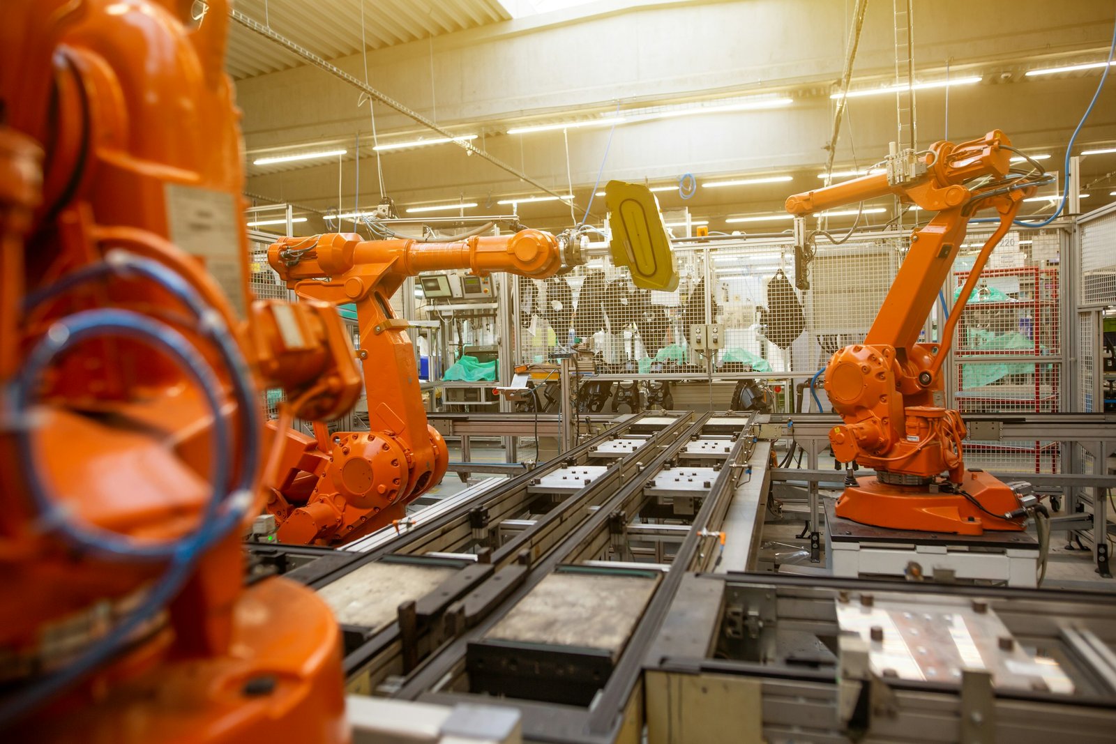 Brazos robóticos naranjas en una línea de producción automatizada