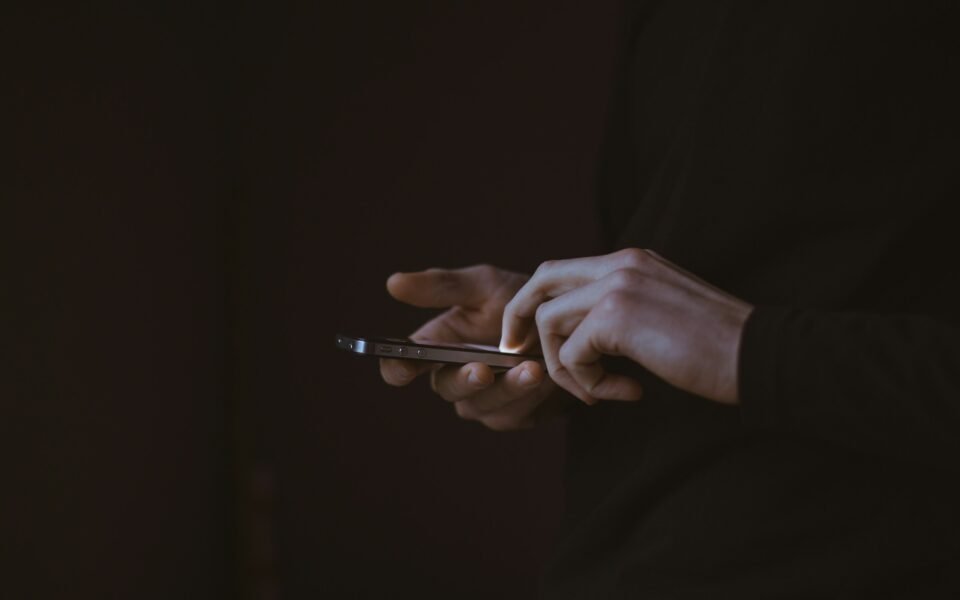 Manos que manejan un teléfono móvil sobre fondo oscuro