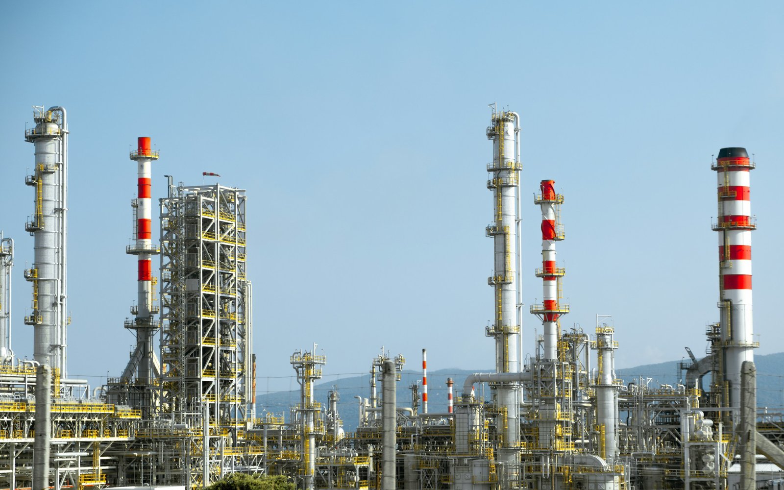 Columnas y chimeneas de una planta industrial mediterránea con montes al fondo