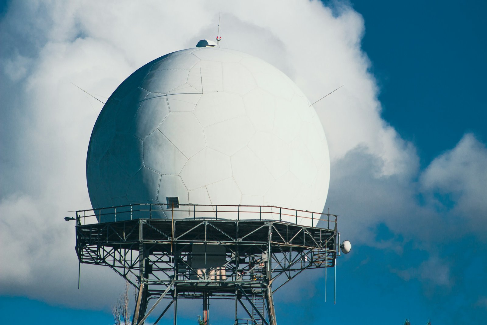 Radomo blanco de radar sobre una plataforma metálica entre nubes