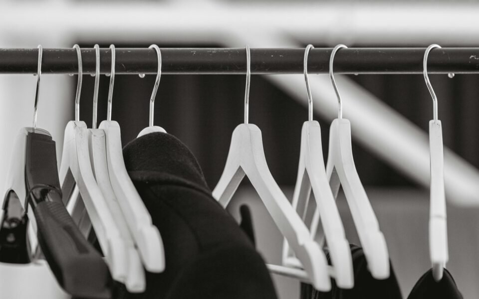 Perchas blancas casi vacías colgadas de una barra en blanco y negro