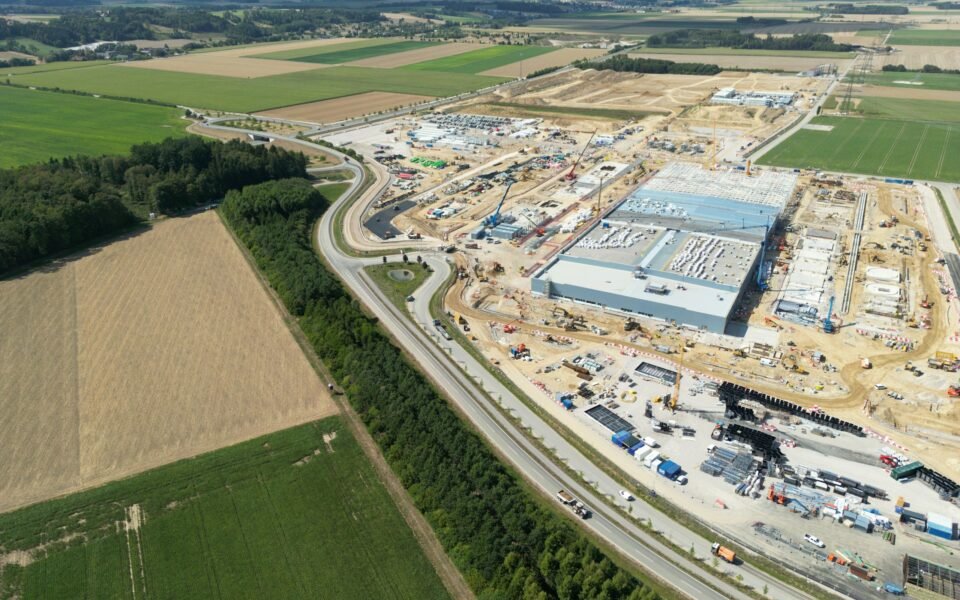 Vista aérea de una gran obra industrial entre campos de cultivo y una autovía