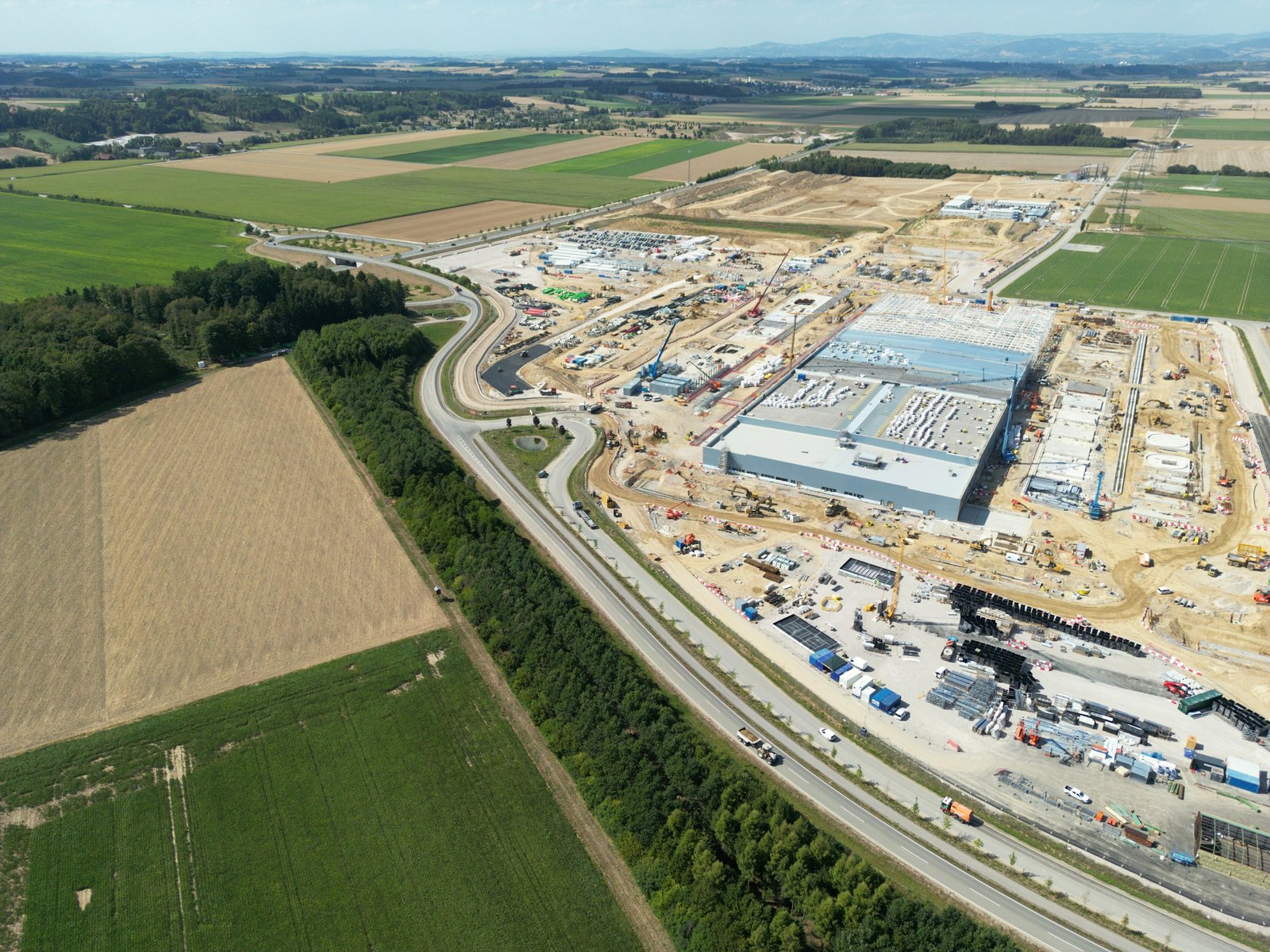 Vista aérea de una gran obra industrial entre campos de cultivo y una autovía