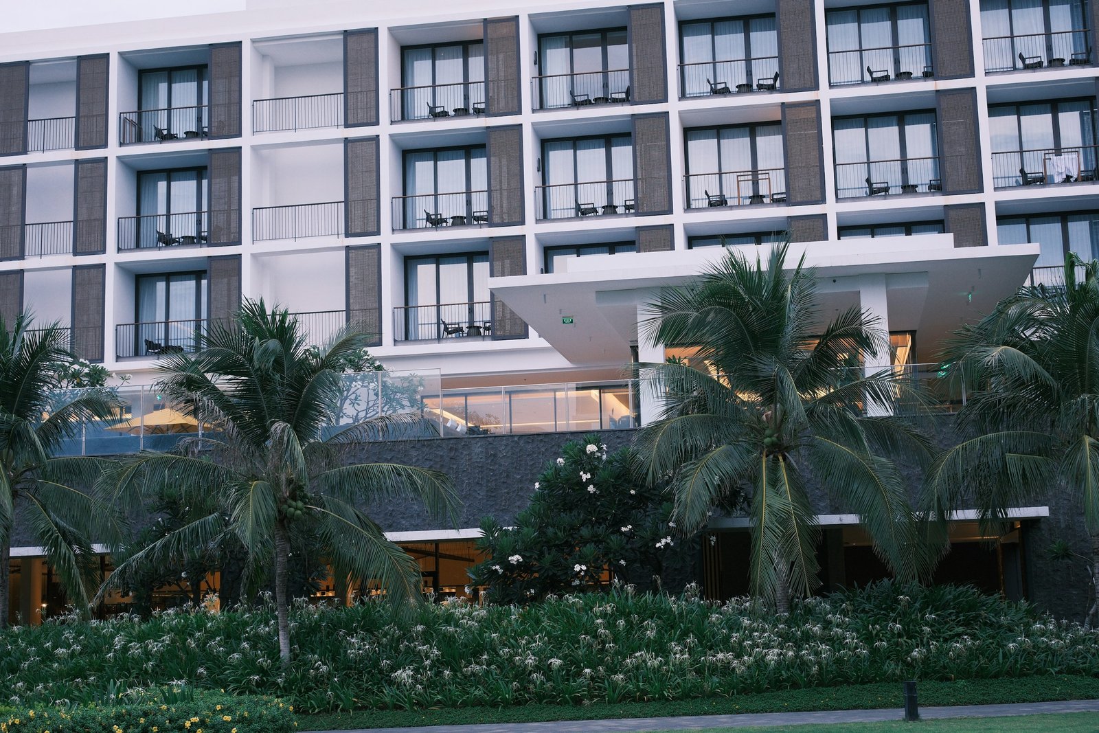 Fachada de un hotel moderno con balcones y palmeras