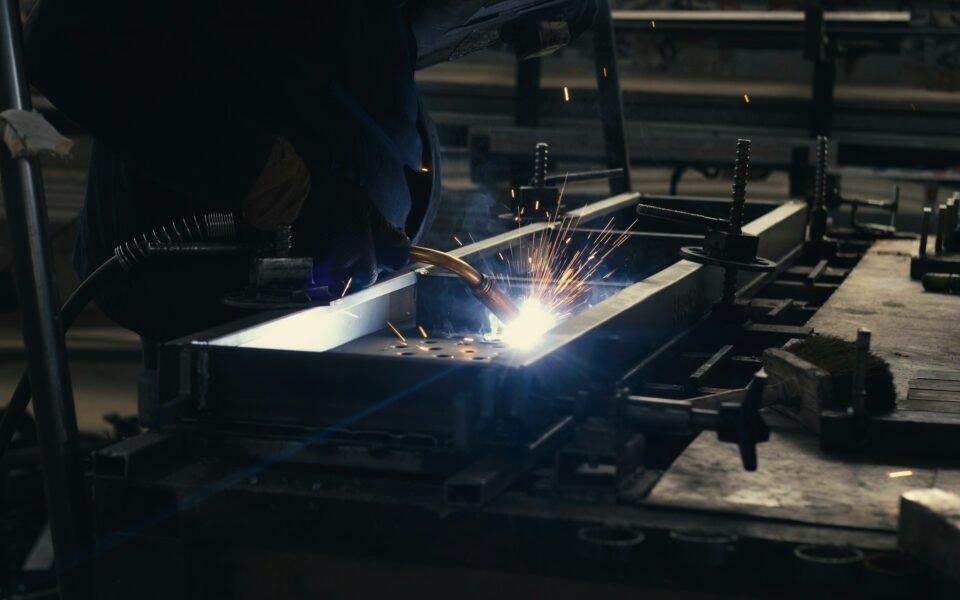 Soldador uniendo una estructura de acero entre chispas en un taller