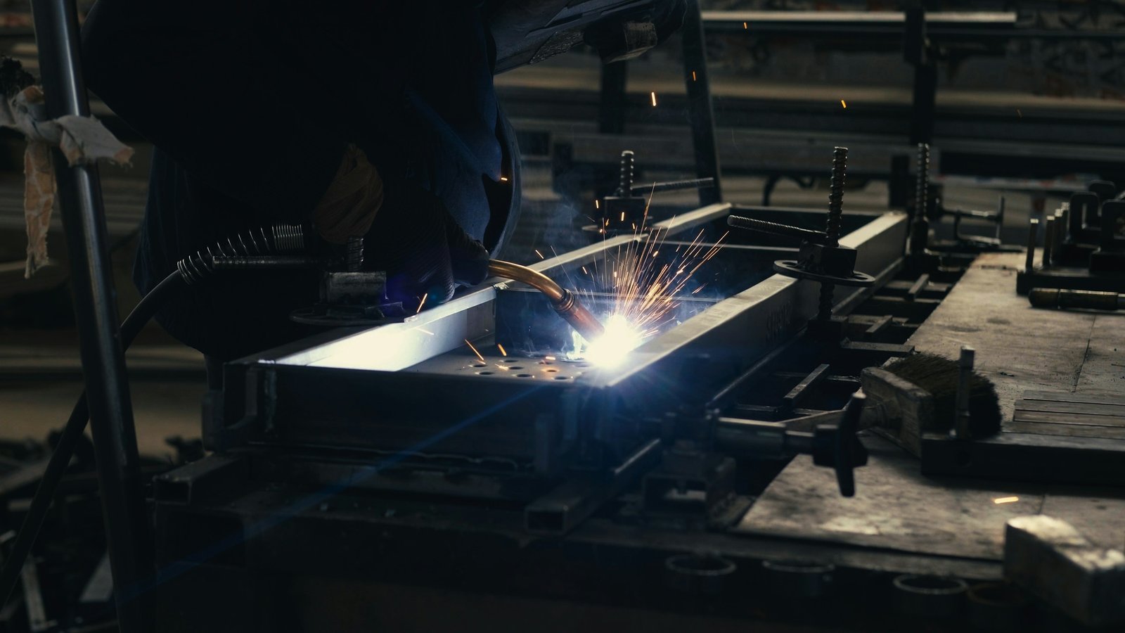 Soldador uniendo una estructura de acero entre chispas en un taller