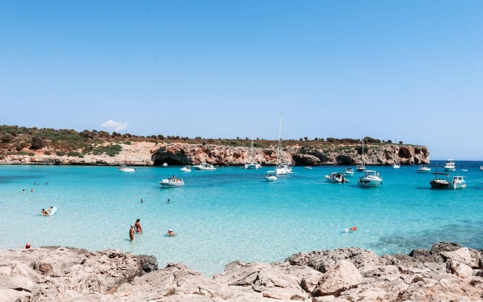 Bañistas y barcos fondeados en una cala de aguas turquesa