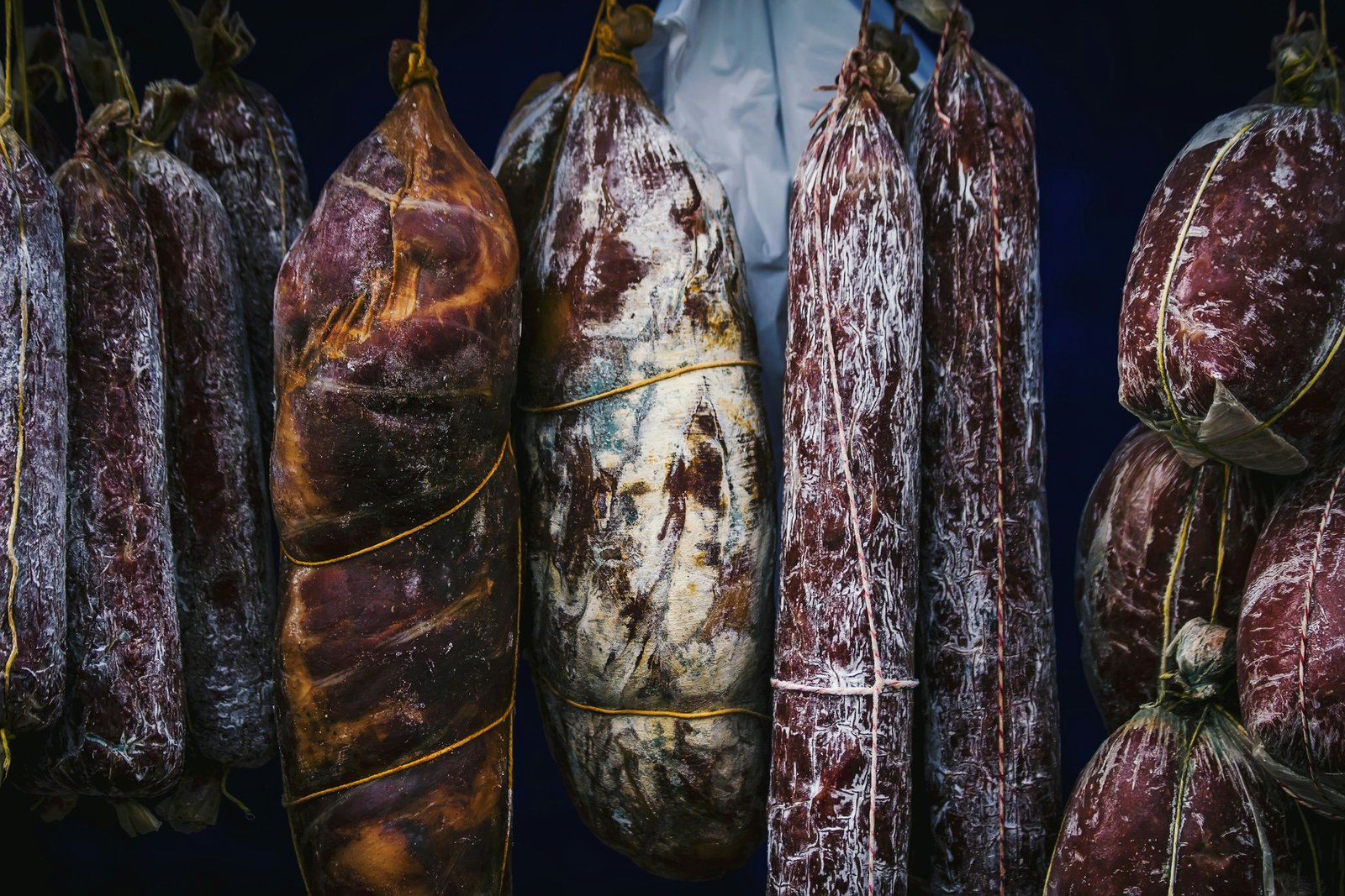 Embutidos curados colgados con cuerda, cubiertos de moho blanco